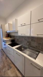 una cucina con mobili bianchi e un lavello di Etna charme apartment a Catania Altre 17 foto