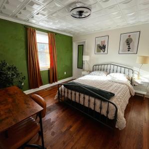 a bedroom with a bed with green walls and wooden floors at Augi's Den. Close to Masters. Modern. Fun in Augusta