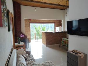 un soggiorno con divano e grande TV di Casa Mohini a Teresópolis
