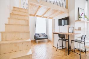 a living room with a wooden staircase and a tv at Studio cosy avec mezzanine calme hypercentre Villa Marie Celine in Vichy