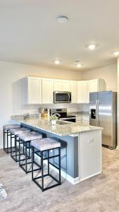 卢雷Luray Caverns New Townhome with 3 bedrooms with 1500sqft的厨房配有白色橱柜和带凳子的台面