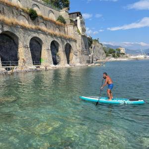 a man standing on a paddle board in the water at B&B DieMme Amalfi Coast in Vietri
