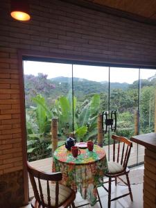 a table and chairs on a balcony with a view at Casa Mohini in Teresópolis