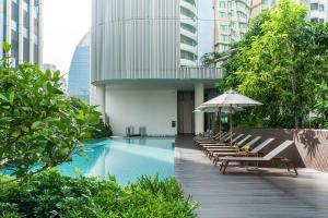 una piscina con bancos y una sombrilla en un edificio en Central Siam Chitlom Superb Luxury 80sqm, en Bangkok