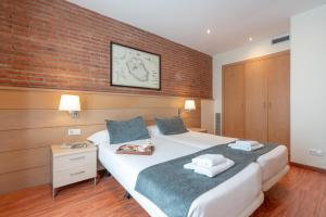 1 dormitorio con cama y pared de ladrillo en Serennia Cest Apartamentos Arc de Triomf, en Barcelona