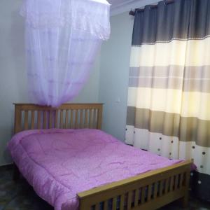 een slaapkamer met een bed met paarse lakens en gordijnen bij V.S.C Courts in Kampala