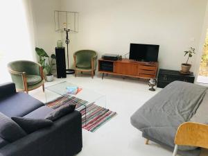 a living room with a couch and chairs and a tv at Maison Surf & Nature à Hendaye in Hendaye