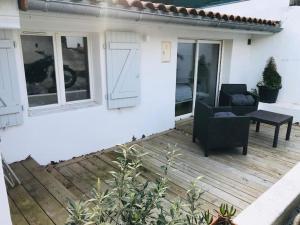 a patio with a black chair on a wooden deck at Maison Surf & Nature à Hendaye in Hendaye