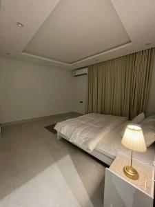 شقة فاخرة بتصميم مودرن و دخول ذاتي حي غرناطة بالرياض في الرياض: غرفة نوم بسرير وطاولة مع مصباح