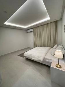 شقة فاخرة بتصميم مودرن و دخول ذاتي حي غرناطة بالرياض في الرياض: غرفة نوم بيضاء فيها سرير ومصباح