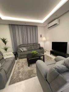 شقة فاخرة بتصميم مودرن و دخول ذاتي حي غرناطة بالرياض في الرياض: غرفة معيشة بها كنبتين وتلفزيون