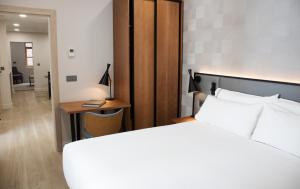 1 dormitorio con cama, escritorio y mesa en Prisma Suites en Salamanca