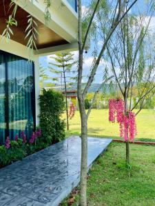 Una casa con un árbol con flores rosas. en มาริลิน พูลวิลล่า ขนอม, 