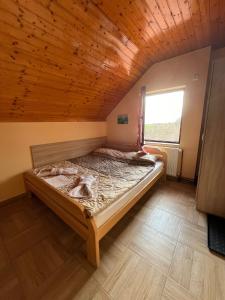 uma cama num quarto com tecto em madeira em Fruškogorska Lugarnica em Mala Remeta