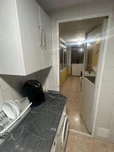 cocina con armarios blancos y encimera negra en Habitación privada en piso compartido Madrid, en Madrid