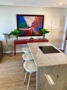 a kitchen with a counter and stools and a painting at 6 Dolphin Views La Mercy Beachfront in La Mercy