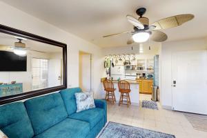 a living room with a blue couch and a kitchen at Fairway Terrace G101 in Waikoloa Village