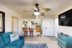 a living room with a blue couch and a ceiling fan at Fairway Terrace G101 in Waikoloa Village
