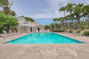 a swimming pool in front of a house with palm trees at Fairway Terrace G101 in Waikoloa Village