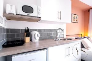 a kitchen with white cabinets and a microwave at Gorgeous Longton Studio 2a in Stoke on Trent