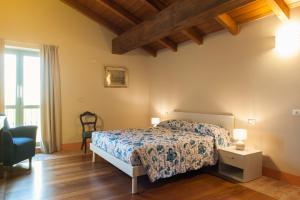 a bedroom with a bed and a chair at Agriturismo Le Tre Rose - Cantina Zanello in Rosignano Monferrato
