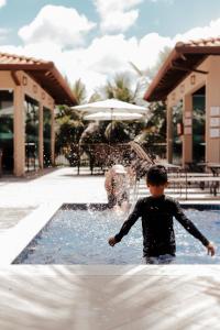 un joven parado en un charco de agua en Pousada Kanto Suites & Spa, en Capitólio