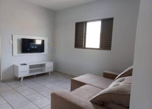 a living room with a couch and a tv at Casa da Iná! Com piscina e churrasqueira! in Rio Verde