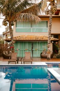 a house with two chairs next to a swimming pool at Pousada Kanto Suites & Spa in Capitólio