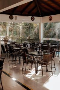 een eetkamer met tafels, stoelen en ramen bij Pousada Kanto Suites & Spa in Capitólio