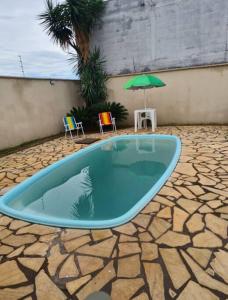 a swimming pool with two chairs and an umbrella at Casa da Iná! Com piscina e churrasqueira! in Rio Verde