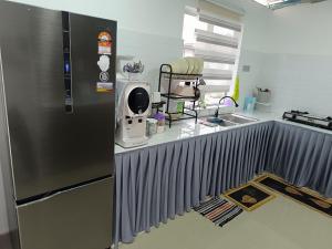 a kitchen with a stainless steel refrigerator next to a sink at JRC Homestay Kerteh in Kampung Sekuang