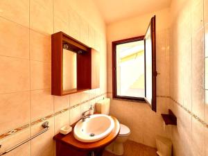 a bathroom with a sink and a toilet and a window at Natural Home, Villasimius in Villasimius