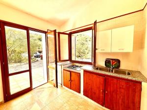 a kitchen with wooden cabinets and a sink and windows at Natural Home, Villasimius in Villasimius