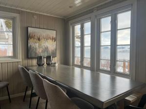 a large table with chairs in a room with windows at Centrally Located Cabin by the Sea - Sortland in Sortland