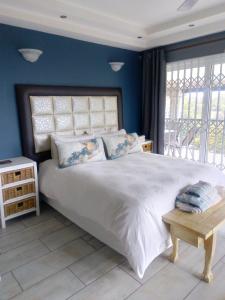 a bedroom with a large white bed with blue walls at Burd's Nest 215 in Shelly Beach