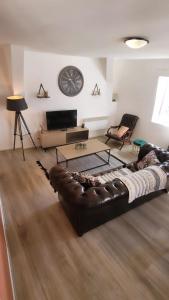 sala de estar con sofá de cuero y reloj en la pared en T3 rénové en face des Thermes, en Néris-les-Bains
