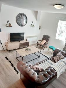 uma sala de estar com um sofá de couro e uma televisão em T3 rénové en face des Thermes em Néris-les-Bains