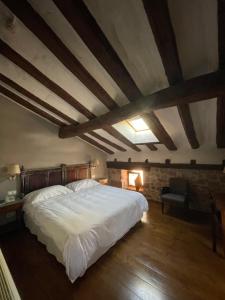 a bedroom with a large white bed and wooden ceilings at Hotel Rural LATORRIÉN DE ANE in Mues