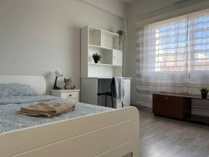 a white bedroom with a bed and a window at Quiet place in Limassol