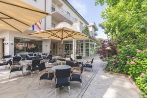 un patio al aire libre con mesas, sillas y sombrillas en Hotel Athena, en Cervia