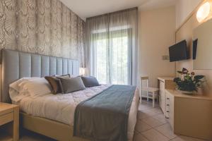 a bedroom with a bed and a desk and a television at Hotel Athena in Cervia