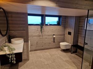 a bathroom with a sink and a toilet andwindows at Ny, eksklusiv hytte til leie på Voss in Skulestadmo
