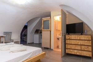 Cet appartement comprend une chambre avec un lit, une télévision et une cuisine. dans l'établissement Leon Lux Apartments, à Perivolos
