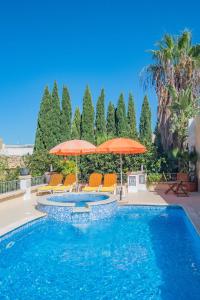 a swimming pool with orange umbrellas and chairs at Central villa flatlet with pool - free parking and WiFi in Lija