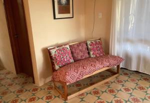a couch with pillows sitting in the corner of a room at Casita Amarilla in the Yellow City in Izamal