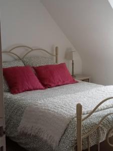 Una cama con dos almohadas rosas encima. en chambre avec vue sur les marais salants en Guérande