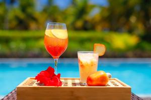 dos bebidas en una bandeja de madera junto a una piscina en Pousada Samba Pa Ti, en Porto de Pedras
