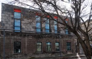 a brick building with red windows and a tree at Erkan Alek Heritage Hotel in Gyumri