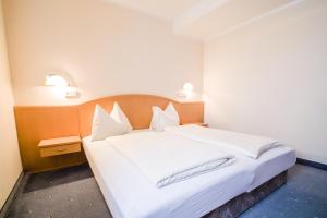 een slaapkamer met een groot bed met witte lakens en kussens bij Landhaus Gretl by S4Y in Krumpendorf am Wörthersee