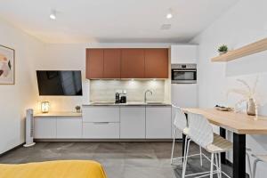 a kitchen with white cabinets and a wooden table at Classy Studio near to Cloche d'Or in Luxembourg